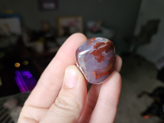 A hand holding a semi-transparent and red crystal.