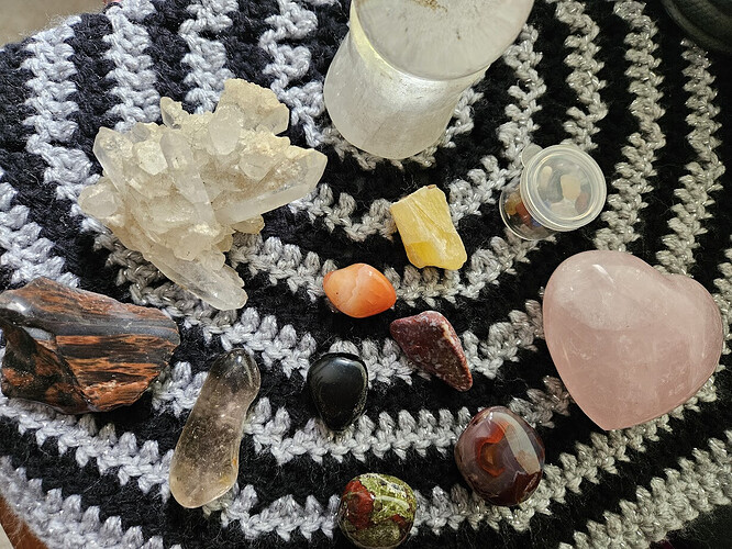 A collection of crystals displayed on a black and silver crocheted cloth.