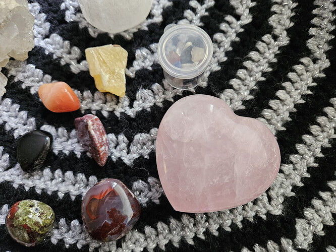 A collection of crystals displayed on a black and silver crocheted cloth.