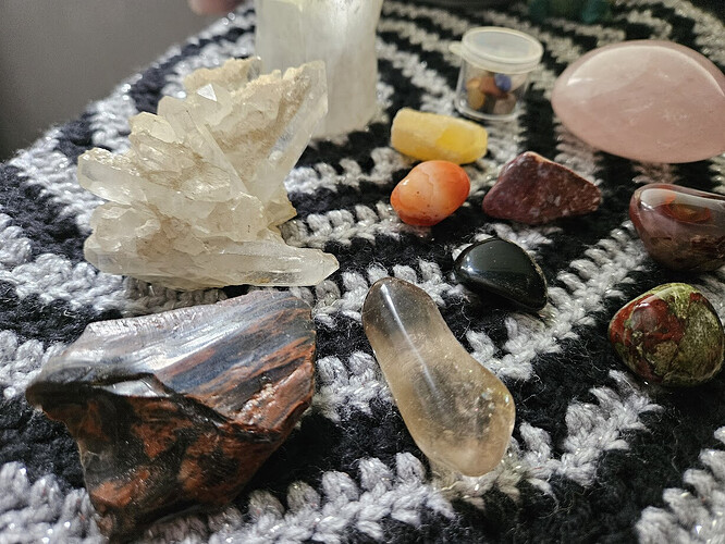 A collection of crystals displayed on a black and silver crocheted cloth.